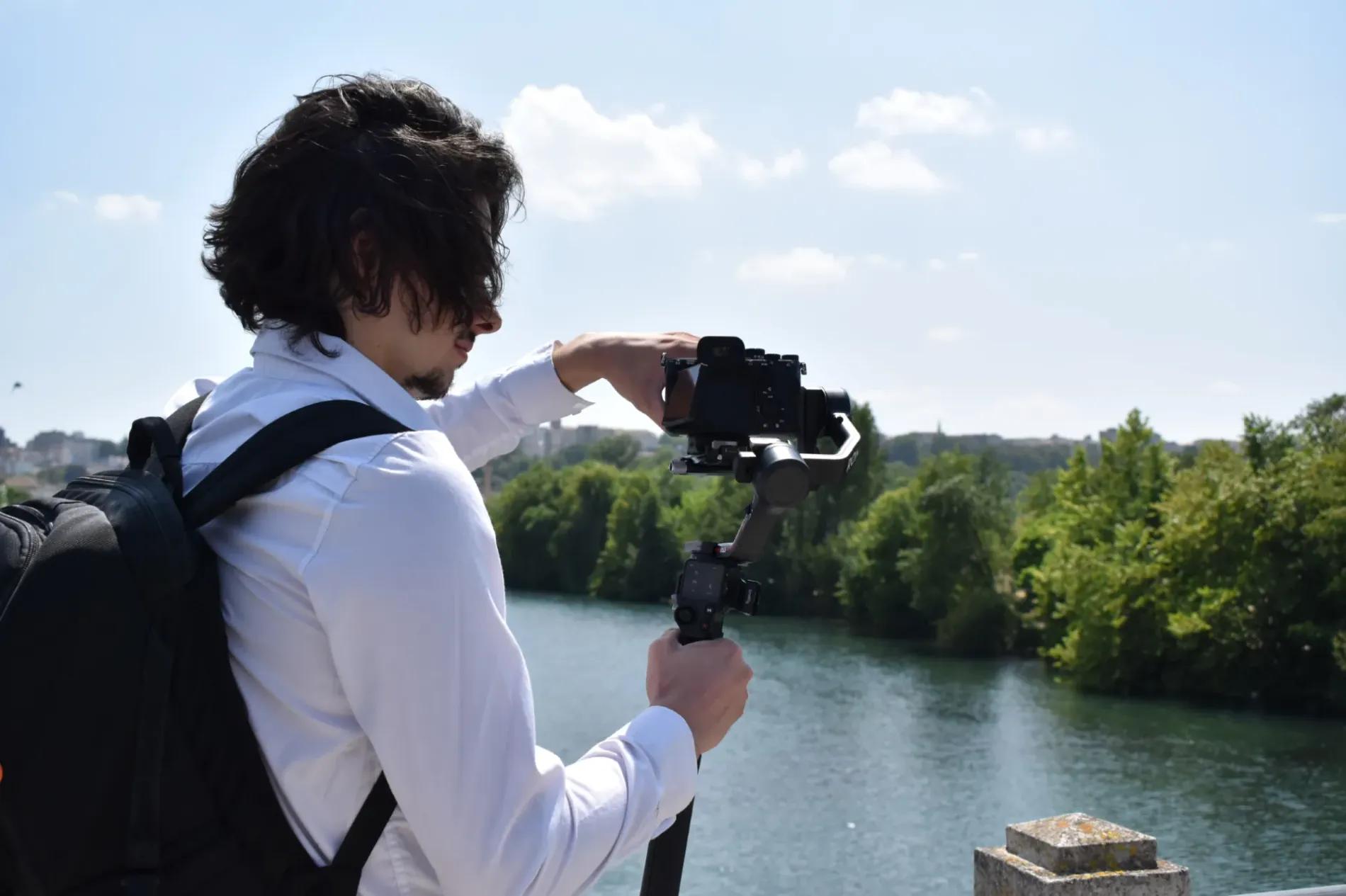Un vidéaste ajuste son matériel avant de filmer une scène en extérieur.